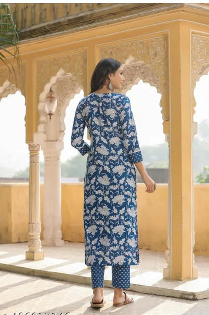 Woman wearing a blue and white patterned kurta with pants in an outdoor setting with architectural columns.