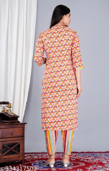Woman wearing a colorful patterned kurta with striped pants against a gray wall.