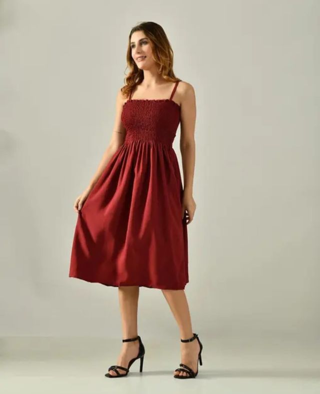 Woman wearing a maroon dress against a plain background