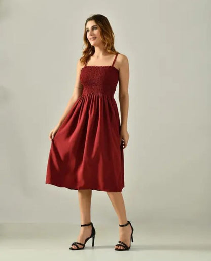 Woman wearing a maroon dress against a plain background