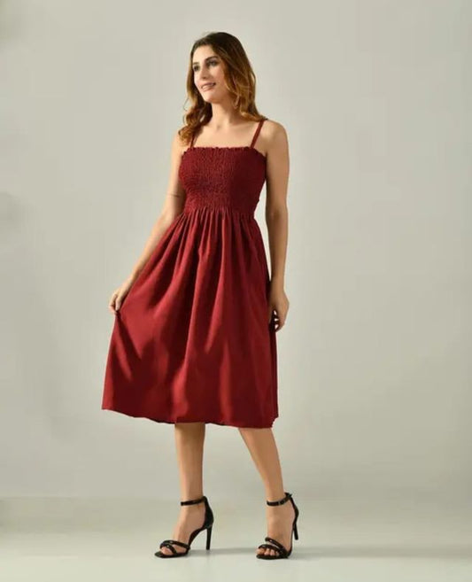 Woman wearing a maroon dress against a plain background