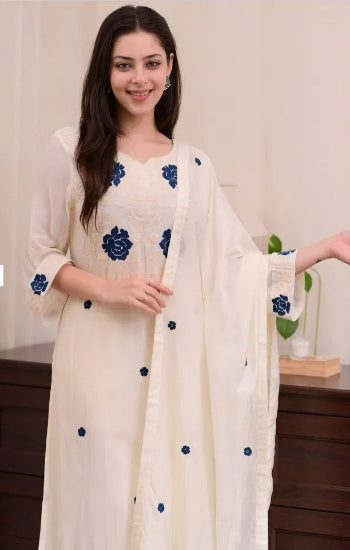 Woman wearing a white outfit with blue floral patterns in a neutral setting